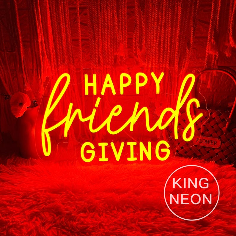 May include: A neon sign with the words "HAPPY friends GIVING" in yellow script. The sign is set against a red background, with a fluffy red surface below. The words "KING NEON" are in a white circle in the bottom right.
