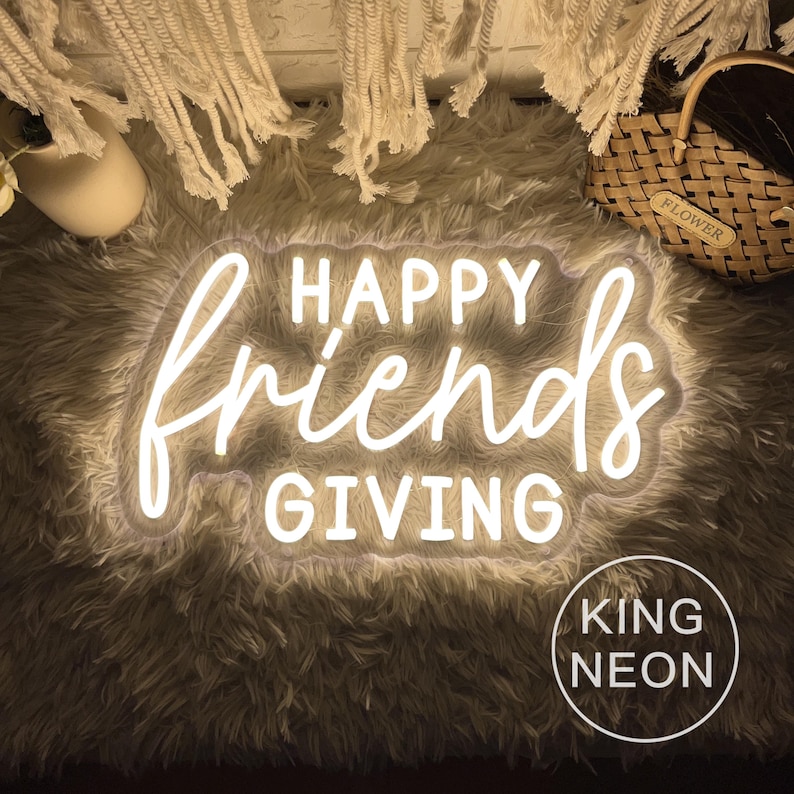 May include: A neon sign with the words "HAPPY Friends GIVING" in white script. The sign is surrounded by a fluffy, light-colored rug. The words "KING NEON" are in a white circle at the bottom.