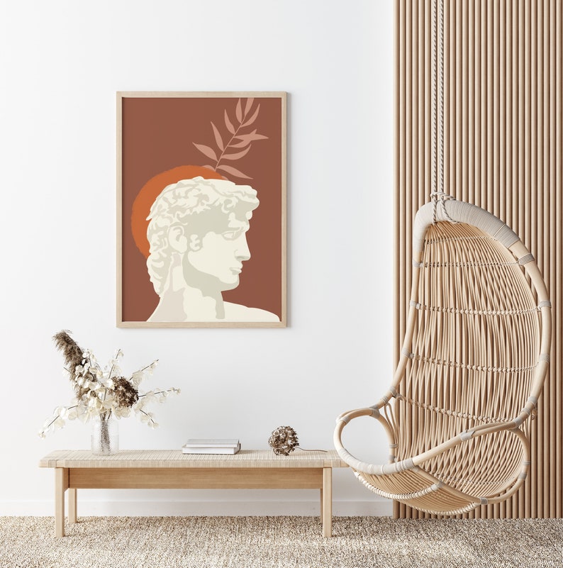 Pu&ograve; includere: Una stampa incorniciata di un busto bianco di un uomo con uno sfondo marrone e un design a foglia. Il busto &egrave; posizionato contro un cerchio rosso. La stampa &egrave; appesa a una parete bianca sopra un tavolo di legno con una sedia a dondolo in vimini sullo sfondo.