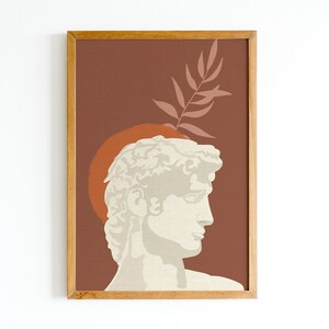 Pu&ograve; includere: Una stampa incorniciata con un design minimalista che presenta una scultura bianca della testa di un uomo su uno sfondo marrone e una foglia rosa.