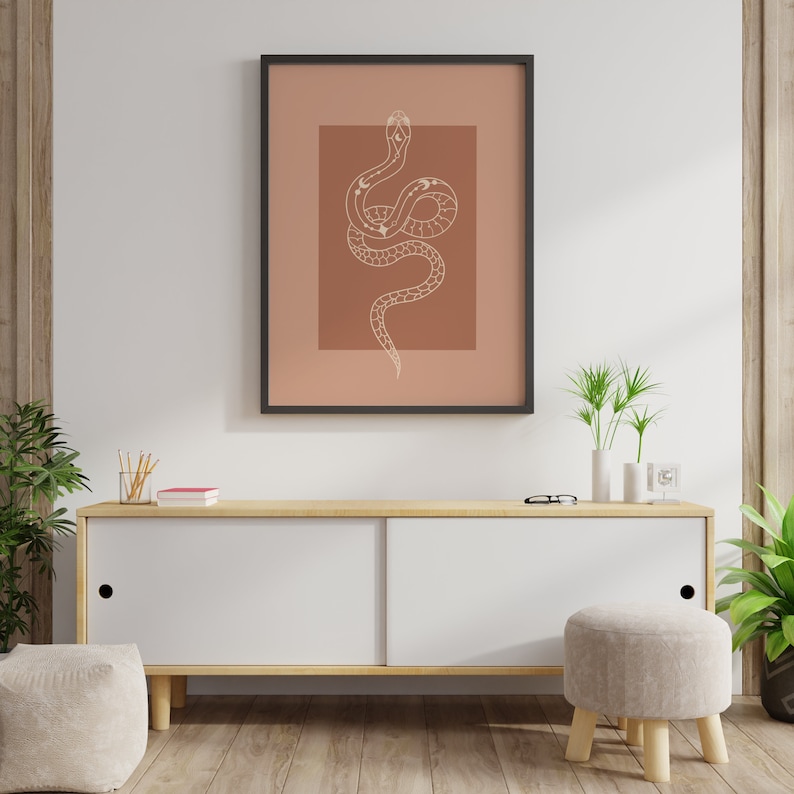 May include: A framed print of a white snake with a brown background. The snake is curled up with its head raised. The snake is decorated with white dots and lines.