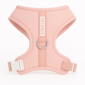 May include: A light pink dog harness with the text "PETSRUS" on the front. The harness has a D-ring for leash attachment and a white buckle closure. The harness is made of a soft, flexible material.