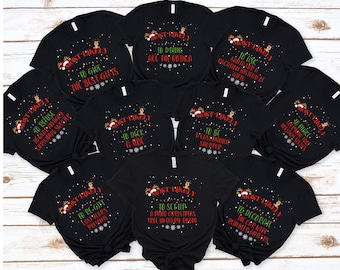 May include: A collection of black t-shirts with various humorous Christmas-themed phrases in red and white. The phrases include "Most Likely to Give the Best Gifts" and "Most Likely to Drink All the Vodka."