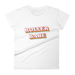 May include: White women's t-shirt with the text "ROLLER BABE" in rainbow colors.