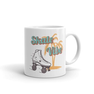 May include: White ceramic mug with a graphic of a roller skate and palm trees. The text "Skate Vibe" is in teal blue letters.