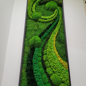 May include: A framed moss wall art piece with a swirling design in shades of green and yellow. The moss is arranged in a variety of textures and shapes, creating a unique and natural look.