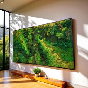 Puede incluir: Una gran obra de arte mural rectangular con una vibrante exhibición de musgo preservado en varios tonos de verde y amarillo. El musgo está enmarcado en un marco rectangular oscuro. La obra de arte está montada en una pared blanca, con un banco de madera debajo.