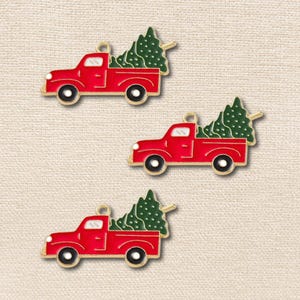 May include: Three metal charms shaped like red pickup trucks, each carrying a green Christmas tree in the truck bed. The charms feature gold-toned metal outlines, black wheels with white centers, and a small loop at the top for attachment.