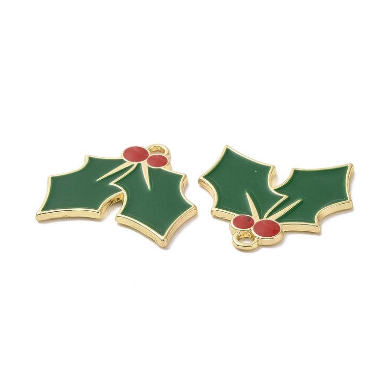 May include: Two holly leaf charms featuring dark green enamel fill and bright red enamel berries. Each charm is outlined in a polished gold-tone metal finish and includes a small circular jump ring at the top for attachment to jewelry or crafts.