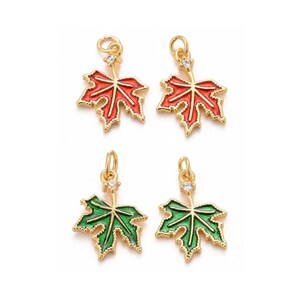 May include: Four gold-tone maple leaf charms with a clear rhinestone in the centre. Two charms are red and two charms are green.