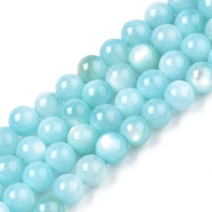 May include: A strand of light blue round gemstone beads. The beads have a smooth, polished finish and a subtle iridescent sheen.