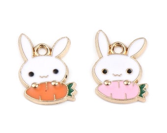May include: Two gold-colored metal charms shaped like rabbits holding carrots. The rabbit on the left is holding an orange carrot, and the rabbit on the right is holding a pink carrot.