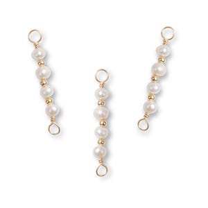 May include: Three strands of white pearls and gold beads. Each strand has a small loop at the top and bottom, connected by gold wire. The pearls are round and evenly spaced, with gold beads between them.