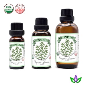 May include: Three amber glass bottles of Organic Zamara Spearmint Oil. Each bottle has a black cap and a white label with green text and a sprig of spearmint. The bottles are labeled 15ml, 30ml, and 60ml.