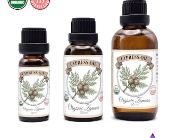 May include: Three amber glass bottles of cypress oil with black caps. Each bottle has a label with the text "CYPRESS OIL" and a botanical illustration. The bottles are labeled "Organic Zamara" and display USDA Organic and Steam Distilled logos.