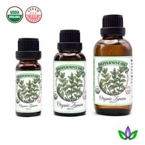 Może przedstawiać: Trzy brązowe szklane butelki olejku z mięty pieprzowej Organic Zamara. Każda butelka ma czarną zakrętkę i białą etykietę z zielonym tekstem i botaniczną ilustracją liści mięty pieprzowej. Rozmiary: 15 ml, 30 ml i 60 ml.