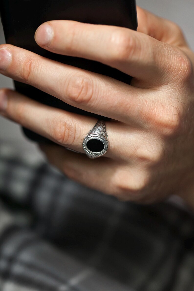May include: A silver ring with a black oval stone set in a decorative band.