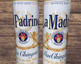 May include: Two white, tall, insulated cups with a gold trim and a black lid. The cups feature a logo with a lion and a barrel, and the text "Cerveceria Modelo" and "Mexico". The text "Padrino" and "La Madrina" are printed on the cups, along with the text "Mas Chingon" and "Las Chingon".