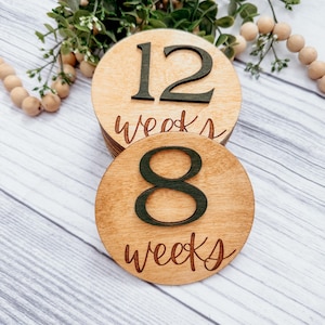 May include: Two wooden circles with the numbers 8 and 12 and the text "weeks" written on them. The circles are stacked on top of each other.