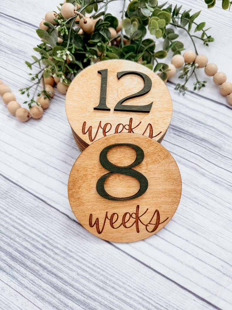May include: Two wooden circles with the numbers 8 and 12 and the text "weeks" written on them. The circles are stacked on top of each other.