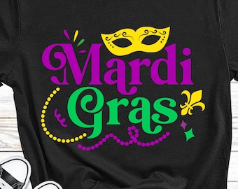 May include: Black t-shirt with the text "Mardi Gras" in purple and green lettering. A yellow mask with purple swirls is above the text. There are purple and gold beads around the text.
