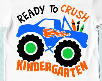 Puede incluir: Un camión monstruo azul con llamas naranjas y una cama llena de crayones y pinceles. El texto "Ready to Crush Kindergarten" está escrito en letras naranjas y negras.
