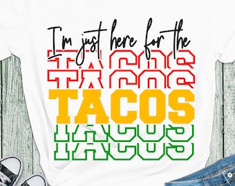 May include: A white t-shirt with the text "I'm just here for the" and the word "TACOS" repeated in red, yellow, and green. The text is in a bold, blocky font.