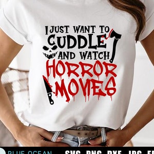 May include: White t-shirt with black text that reads "I just want to cuddle and watch horror movies". The text is decorated with a red dripping effect and a black and white jack-o-lantern face. A black axe and a black knife are also included in the design.