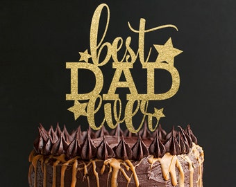 May include: Gold glitter cake topper with the text "best dad ever" and stars. The topper is on top of a chocolate cake with caramel drizzle.