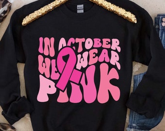 May include: Black sweatshirt with a pink ribbon and the text "In October We Wear Pink" in a retro font.