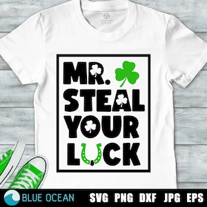 Puede incluir: Camiseta blanca con un gráfico cuadrado negro que dice "Mr. Steal Your Luck" con un trébol verde y una herradura.