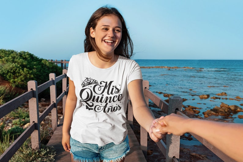 Puede incluir: Una camiseta blanca con texto negro que dice "Mis Quince A&ntilde;os" con una corona sobre la palabra "Mis".