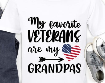 May include: White t-shirt with black text that reads "My favorite VETERANS are my GRANDPAS" with an arrow pointing to a red heart with the American flag design.