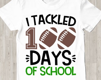 May include: White t-shirt with black text that reads "I tackled 100 days of school" with a large black number 1 and two brown footballs.