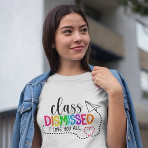 May include: White t-shirt with the text "class DISMISSED I love you all" in rainbow colours with a paper aeroplane and a heart.
