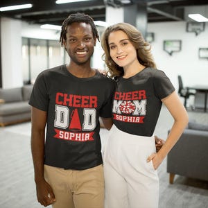 Pode incluir: Um casal vestindo camisetas pretas com tema de torcida. A camiseta do homem diz "Cheer Dad Sophia" e a camiseta da mulher diz "Cheer Mom Sophia".