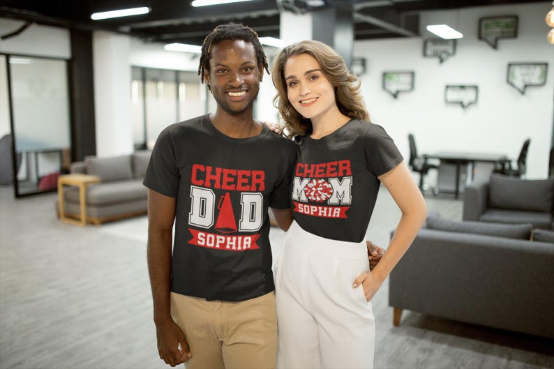 Pode incluir: Um casal vestindo camisetas pretas com tema de torcida. A camiseta do homem diz "Cheer Dad Sophia" e a camiseta da mulher diz "Cheer Mom Sophia".