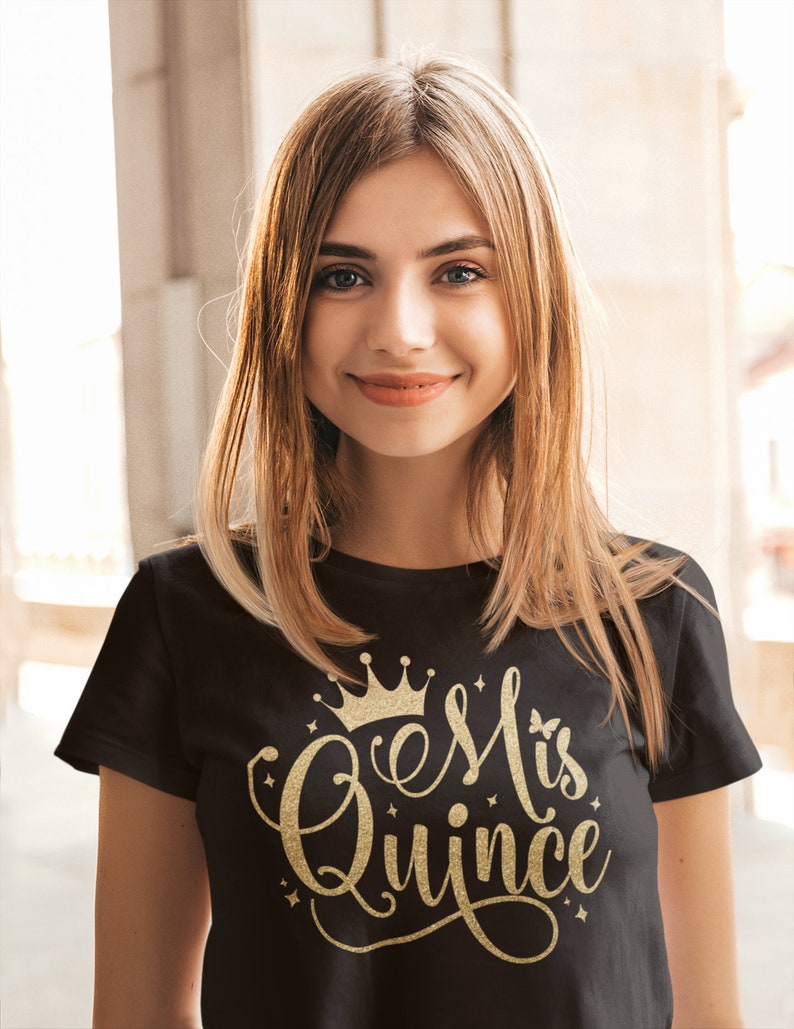 May include: A black t-shirt with a gold glitter design that says "#esMiQuince" with a crown above the text.