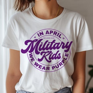 May include: White t-shirt with a purple circle graphic that says "In April We Love Our Military Kids We Wear Purple".