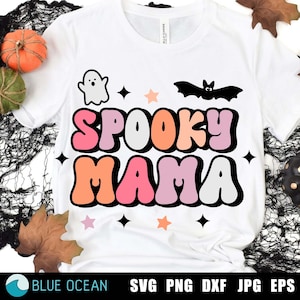 May include: White t-shirt with a colorful "Spooky Mama" graphic. The graphic features a ghost, a bat, and stars in pink, orange, and white.