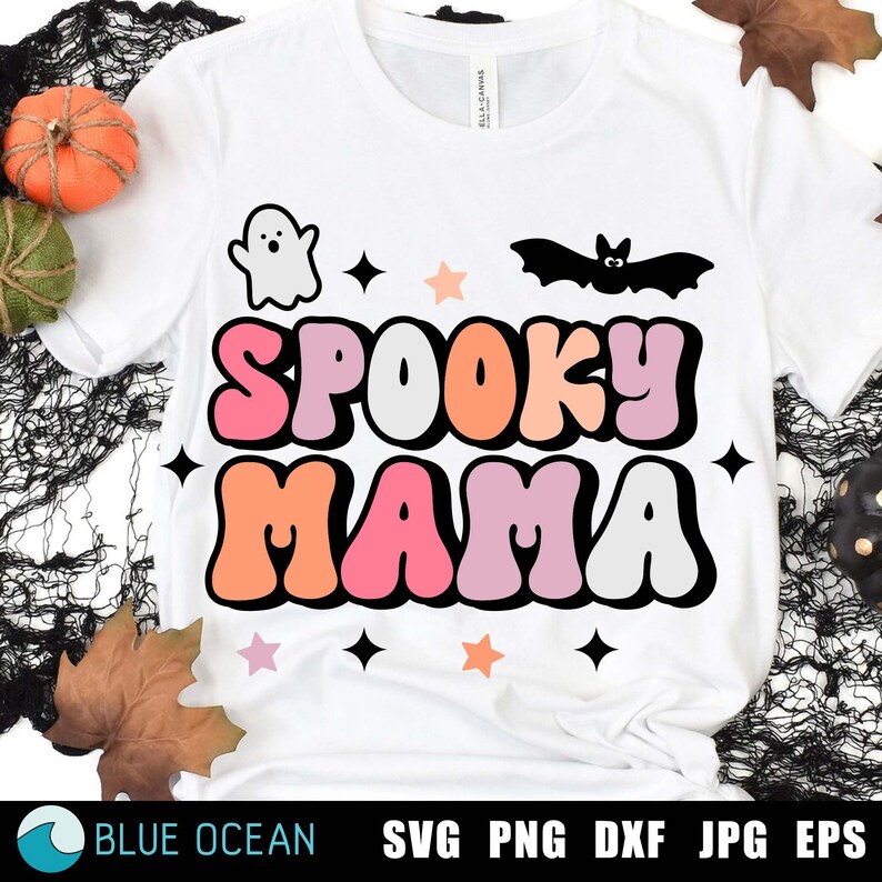 May include: White t-shirt with a colorful "Spooky Mama" graphic. The graphic features a ghost, a bat, and stars in pink, orange, and white.
