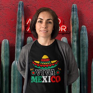 May include: A woman wearing a black t-shirt with a colorful sombrero graphic and the text "Viva Mexico".