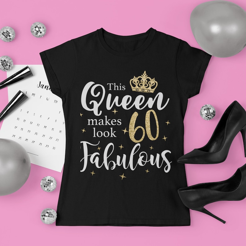 Op de afbeelding: Zwart T-shirt met een gouden glitterkroon en de tekst "This Queen makes 60 look Fabulous".