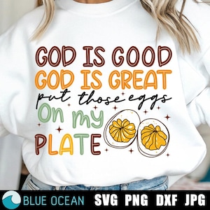 Könnte beinhalten: Weißes Sweatshirt mit dem Text "GOD IS GOOD GOD IS GREAT put those eggs On my PLATE" in Braun, Orange, Grün und Gelb. Unter dem Text befinden sich zwei illustrierte Eier. Der untere Teil des Bildes enthält den Text "BLUE OCEAN SVG PNG DXF JPG".