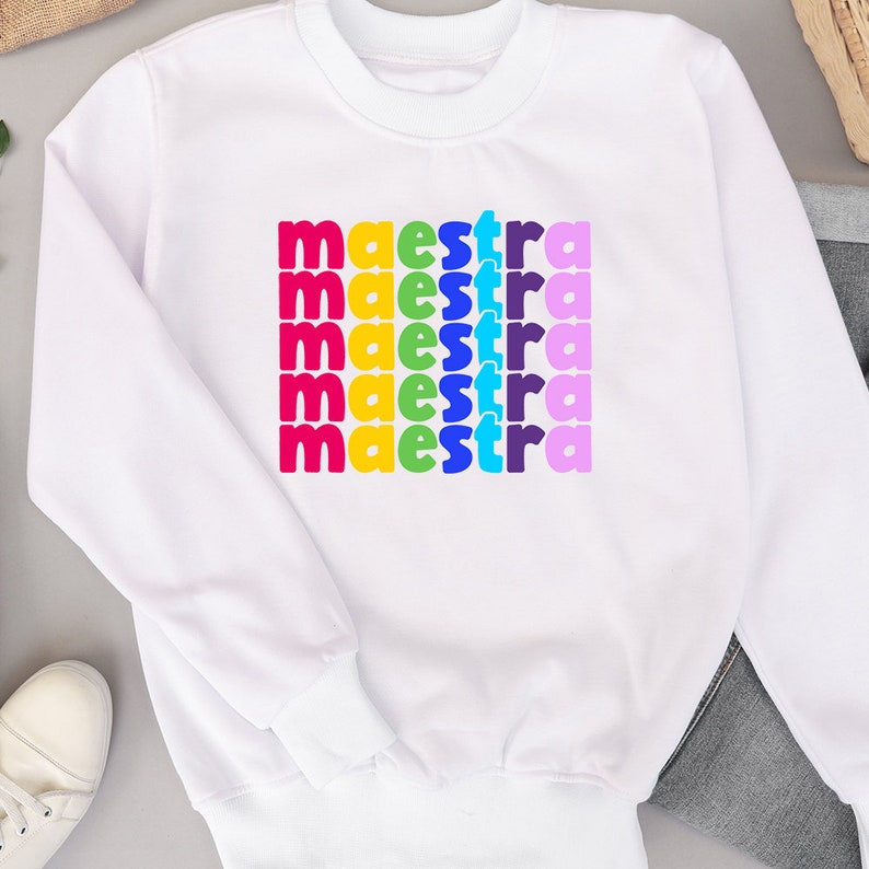 May include: White sweatshirt with the word "maestra" repeated five times in rainbow colours.
