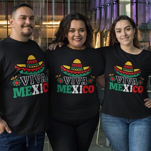 May include: Three people wearing black t-shirts with a colorful sombrero graphic and the text "Viva Mexico".