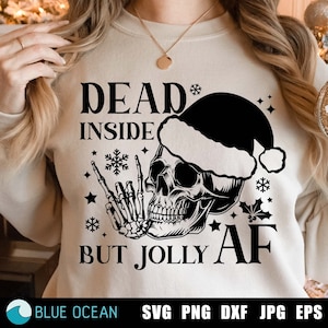 May include: A white sweatshirt with a black skull wearing a Santa hat. The skull is giving the rock and roll hand gesture. The text on the sweatshirt reads "Dead Inside But Jolly AF".