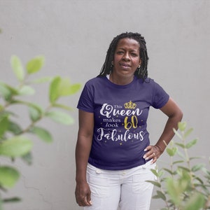 Op de afbeelding: Een vrouw draagt een paars T-shirt met de tekst "This Queen makes 60 look Fabulous" in gouden letters en een gouden kroonafbeelding.