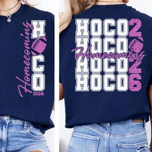 May include: A navy blue t-shirt featuring a vertical graphic that reads Homecoming HOCO 2026 with a pink glitter football. The back design displays the word HOCO stacked four times in white with a pink glitter Homecoming script and 2026.