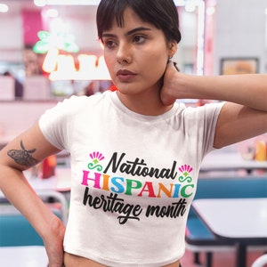 May include: White cropped t-shirt with the text "National HISPANIC heritage month" in colorful letters.